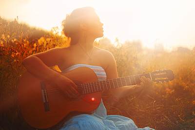 在野外弹奏原声吉他的漂亮女人图片下载