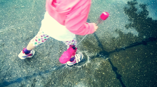 孩子的脚在雨中溅成水坑图片下载