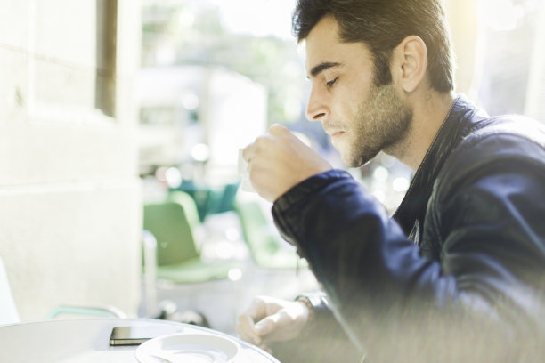 坐在户外喝咖啡的年轻人。图片下载