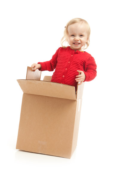 小女孩玩瓦楞纸箱在白色的背景图片下载