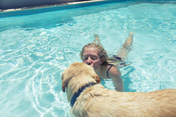 女孩和狗在游泳池里玩图片下载