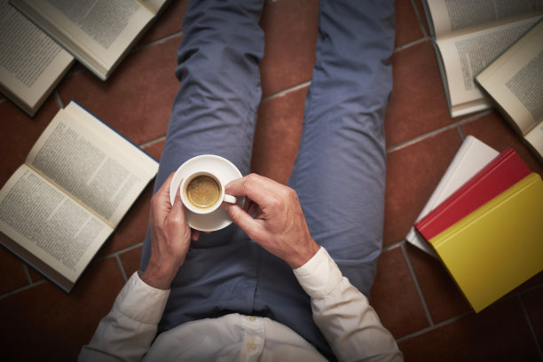 一个人坐在地板上的书中间图片下载