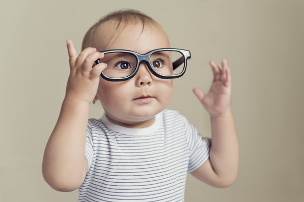 表情丰富的小男孩戴着假眼镜，穿着条纹t恤。图片下载