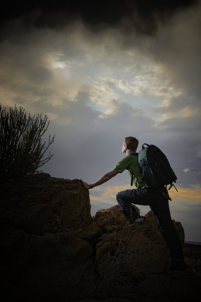 徒步旅行者在山上看着暴风雨的天空图片下载