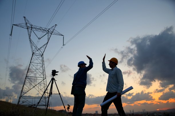 工程师们站在发电站前握手的剪影。图片下载