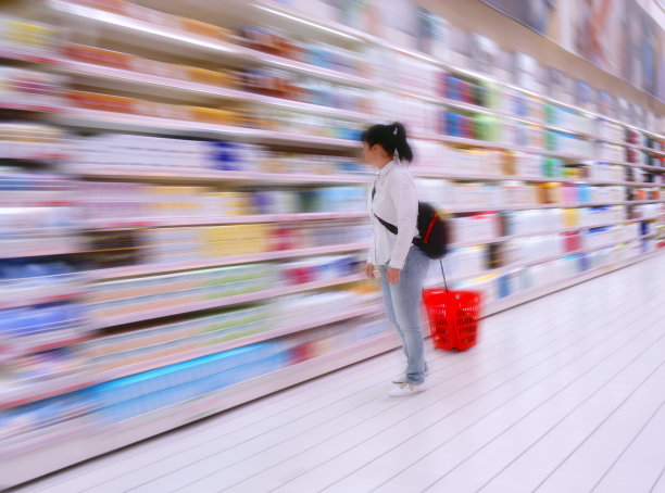 一个女人在超市的货架上摆放着五颜六色的商品图片下载