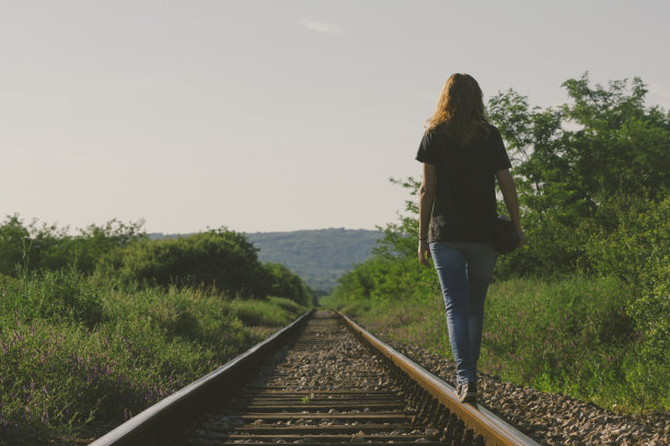 有魅力的女性走在夕阳下的铁路上图片下载