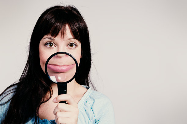 放大镜放大并扭曲了可爱的黑发女郎的微笑图片下载
