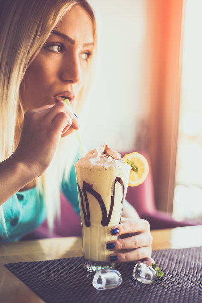 快乐的年轻女子喝着柠檬奶昔图片下载