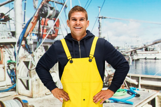 微笑的渔夫站在渔船上图片下载