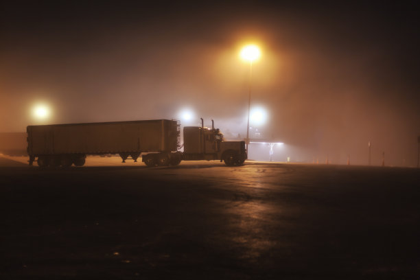 午夜州际高速公路雾蒙蒙的休息站停放的拖车卡车图片下载