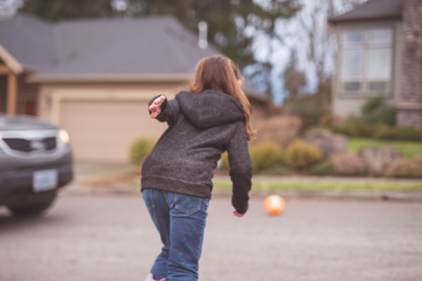 年轻女孩跑到繁忙的街道去拿球图片下载