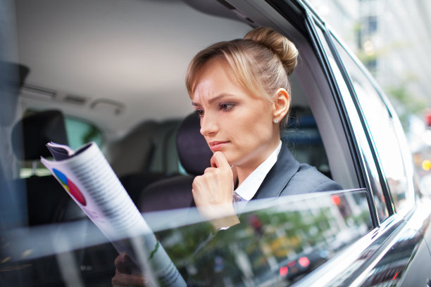 坐在黑色轿车里阅读商业报告的女性高管图片下载