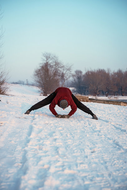 在寒冷的冬日雪地里慢跑、俯卧撑和伸展图片下载