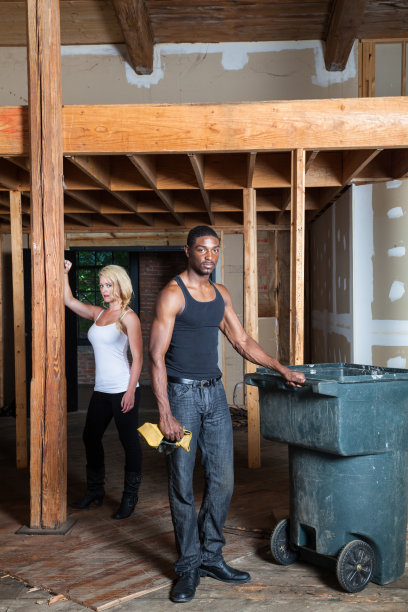 神秘严肃的肌肉发达的非裔美国工人与仓库的手套和t恤与金发白人女性的背景图片下载