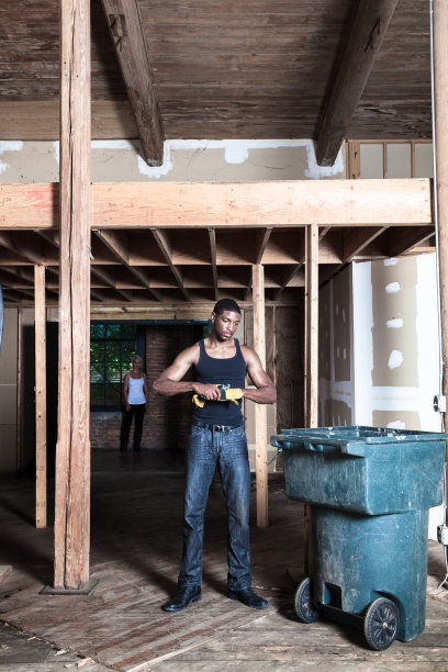 神秘严肃的肌肉发达的非裔美国工人与仓库的手套和t恤与金发白人女性的背景图片下载