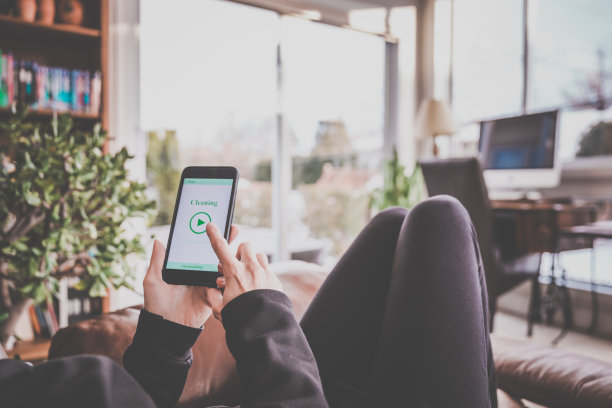 一名女性在手机上使用家庭机器人清洁应用程序图片下载