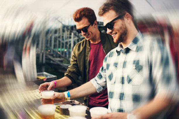 两个微笑的年轻人在小摊上喝啤酒。涡流效应图片下载