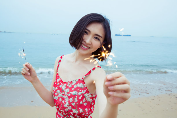 美丽的女人在海滩上玩烟花图片下载