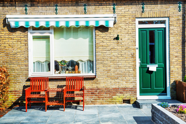 绿色门和木制扶手椅的房子前廊图片下载