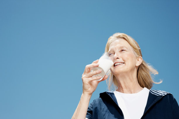 微笑的老妇人喝着牛奶图片下载