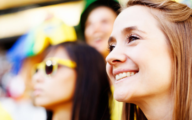 漂亮的金发球迷和朋友在足球比赛微笑图片下载