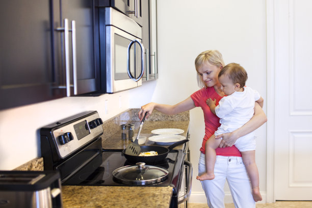 年轻的母亲在厨房做早餐图片下载
