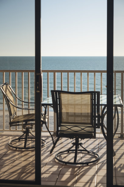 阳台与桌子和椅子俯瞰日落的海洋。图片下载