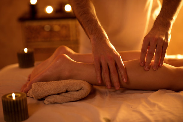 特写按摩治疗师按摩女人的腿。图片下载