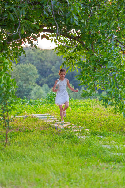小女孩在花园里的小路上奔跑图片下载