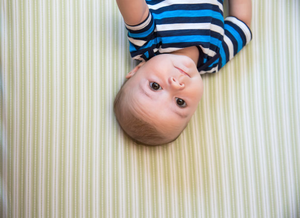小男孩躺在婴儿床上向上看图片下载