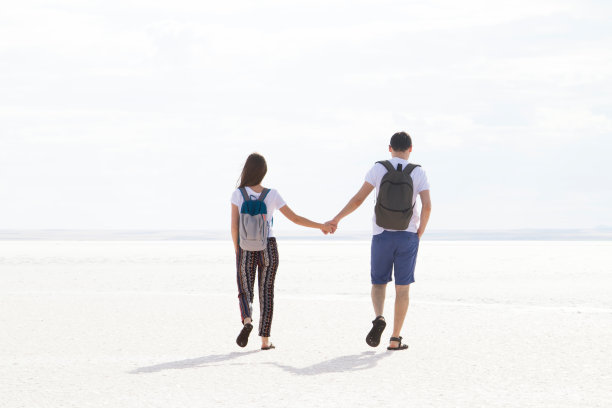 夏日情侣在日落时在盐湖上牵着手。图片下载