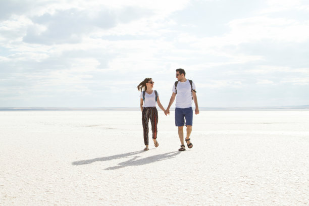 夏日情侣在日落时在盐湖上牵着手。图片下载