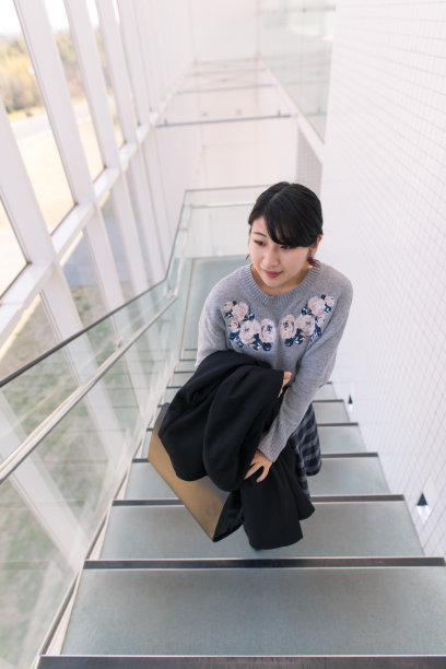 一个年轻女子在白色的大楼里走上楼梯图片下载