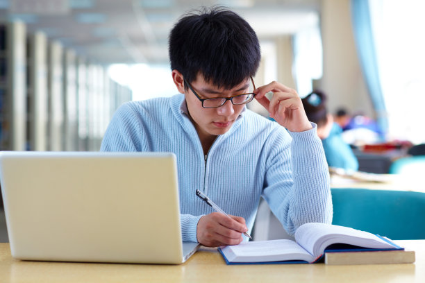 在图书馆用笔记本电脑学习的亚洲男大学生素材图片