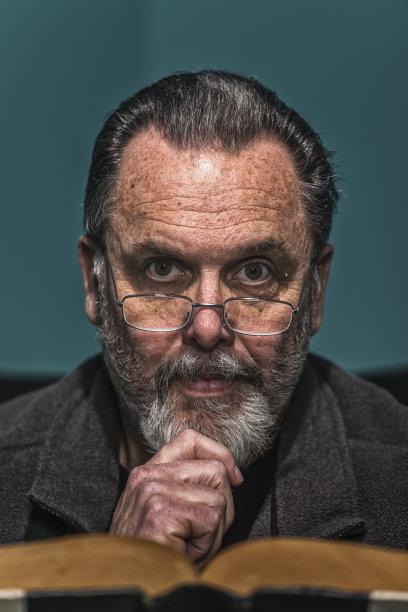 头发花白的男人戴着阅读眼镜读着旧书图片下载