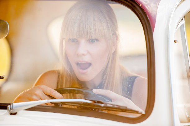迷人的女人驾驶老爷车-透过窗户看图片下载