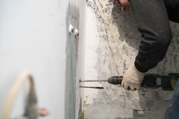 手工建筑工人用凿岩机在墙上钻孔图片下载