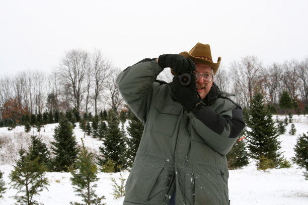 年长的男摄影师戴着牛仔帽在雪地里图片下载