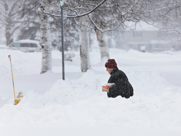 在暴风雪中穿着暖和的女人拿着杂志邮件图片下载