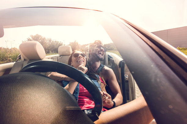 年轻愉快的夫妇在敞篷车里放松和大笑。图片下载