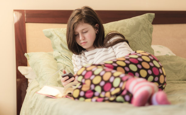 十几岁的女孩穿着睡衣在床上看书图片下载