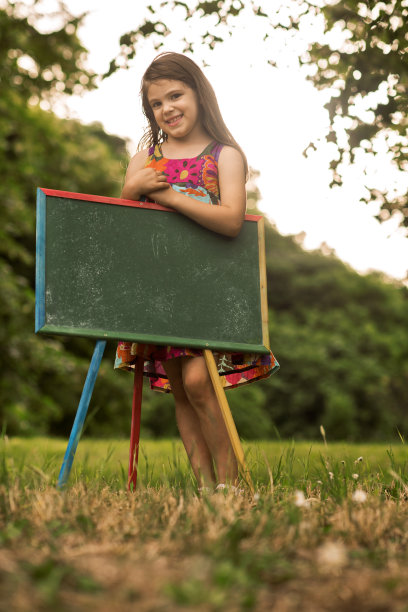 可爱的小女孩拿着黑板在公园里。图片下载