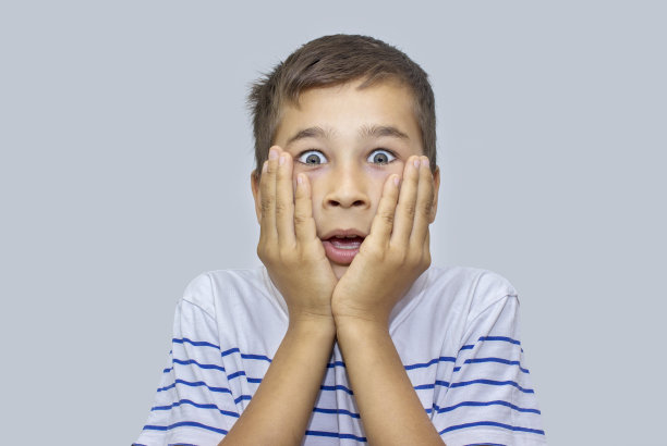灰色背景下惊讶的小男孩的肖像素材图片