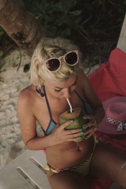 马尔代夫，一名嬉皮女子在棕榈树下喝椰子汁图片下载