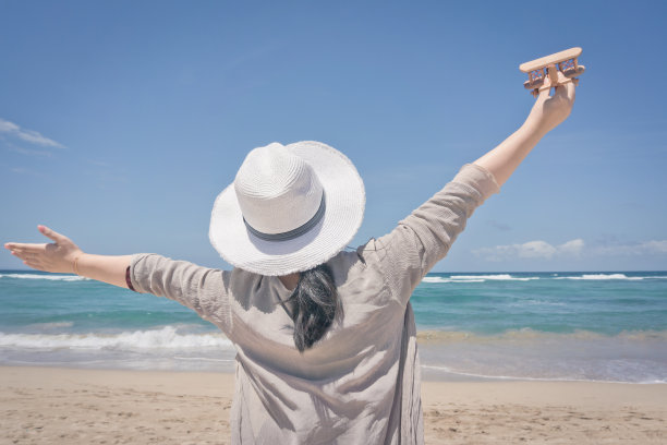 年轻女子在海滩上玩木飞机图片下载