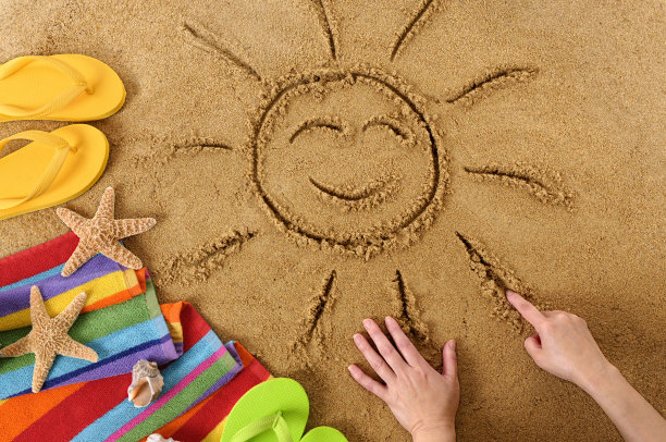 沙画一个快乐的太阳，带着凉鞋，星星和毛巾图片下载