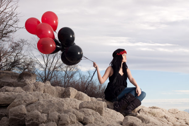 坐在岩石上的女人拿着气球图片下载