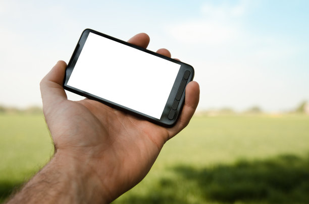 在户外拿着一部白色的智能手机图片下载