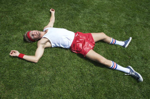 疲惫的运动员躺在绿草地上图片下载